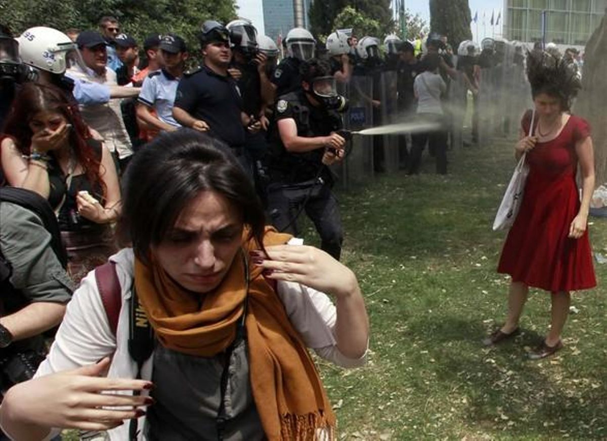 A Turkish riot policeman uses tear gas as people protest against the destruction of trees in a park brought about by a pedestrian project, in Taksim Square in central Istanbul in this May 28, 2013 file photo.