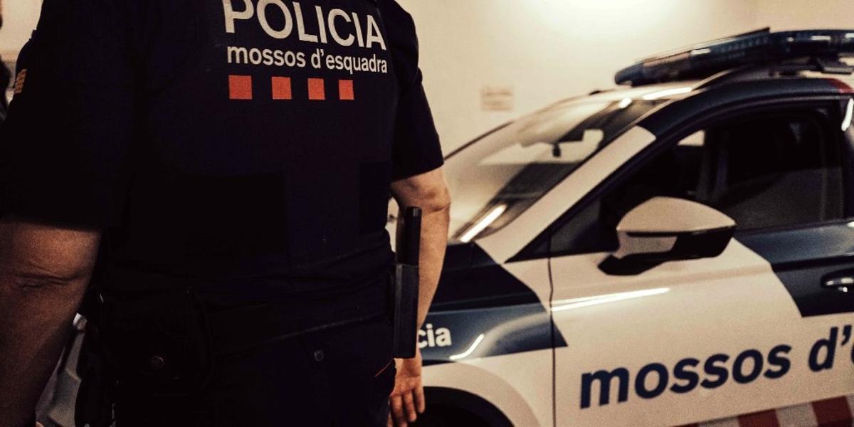 Un agente de los Mossos d'Esquadra junto a un vehículo policial.