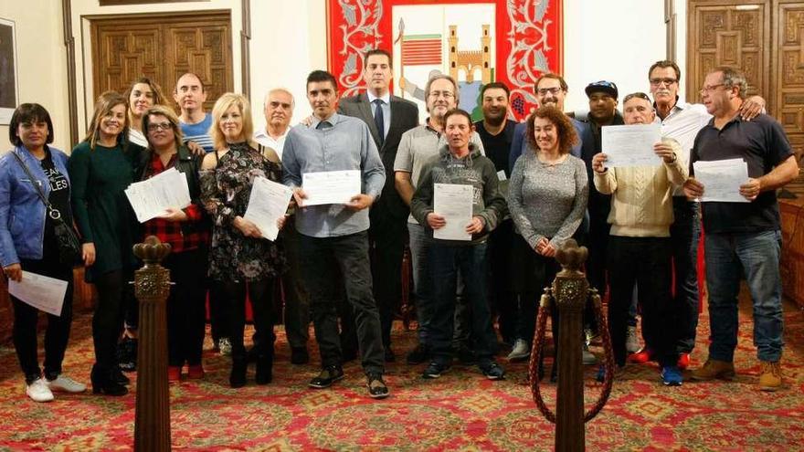 Los doce alumnos posan con sus diplomas en el salón de plenos junto con Francisco Guarido y Alberto Castro, entre otras personas.