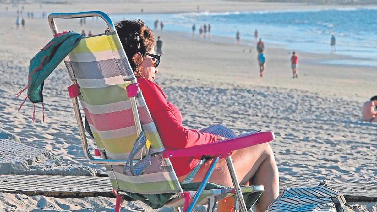 Una señora leyendo un libro en la playa