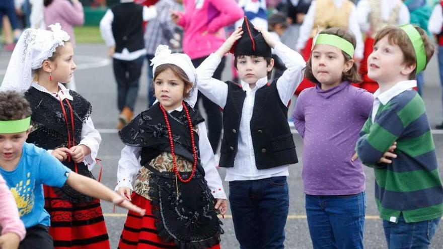 Un científico del Instituto de Productos Lácteos muestra una placa de petri a varios niños del colegio Enrique Alonso. A la derecha, alumnos del Marcos del Torniello, rodeados de compañeros y padres, durante la degustación de sidra dulce y castañas en el patio del centro educativo.