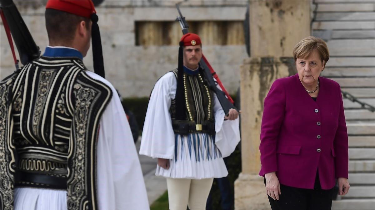 La canciller alemana, Angela Merkel, rinde homenaje en la Tumba del Soldado Desconocido en Atenas. Merkel llegó a Grecia en medio de estrictas medidas de seguridad mientras intenta pasar página de las estrictas medidas de austeridad que provocaron grandes protestas durante su última visita oficial a Atenas.