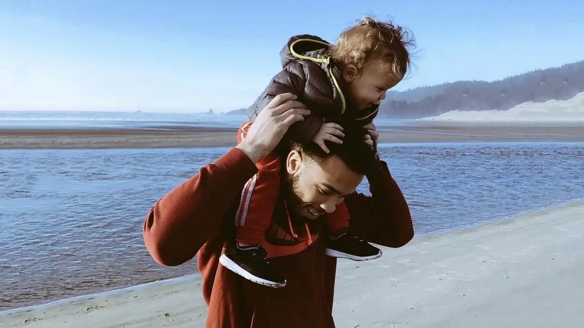 Un hombre lleva en hombros a su hijo.
