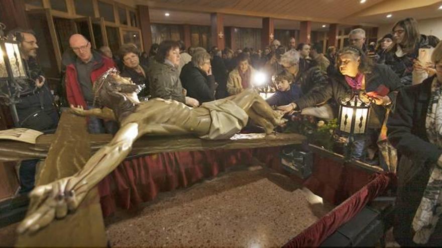 Numerosas personas tocan con fervor el Cristo de las Angustias tras su bajada desde el altar de la iglesia de la Sagrada Familia.