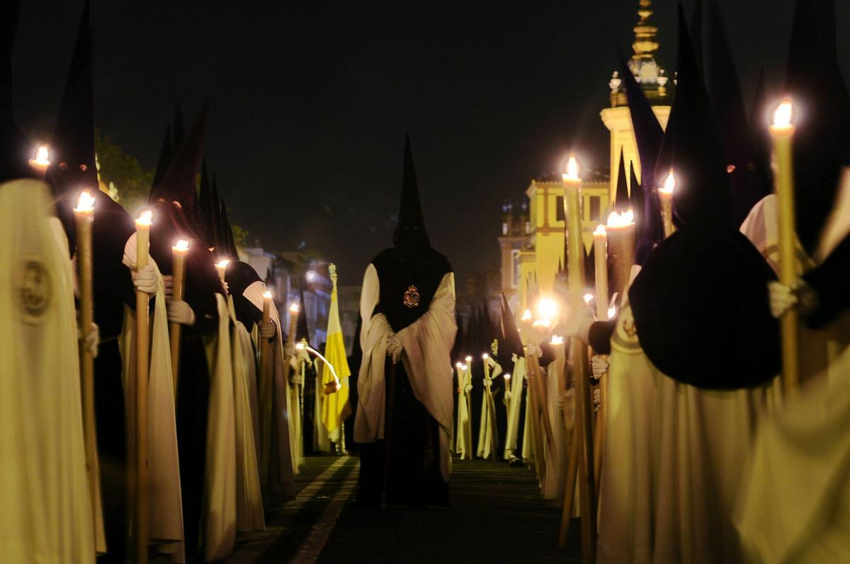 Nazarenos de la Esperanza de Triana cruzan el puente de Triana durante la Madrugá.
