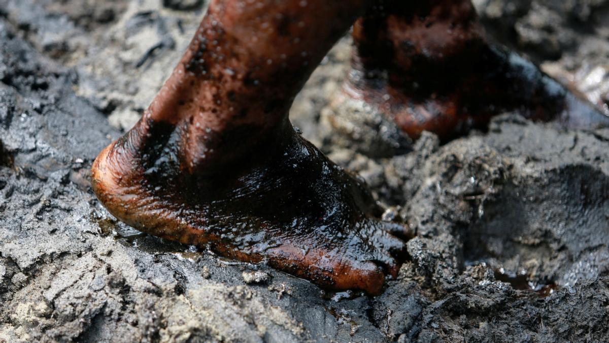 Los pies de un trabajador hundidos en la mancha de petróleo en una refinería ilegal en Okrika