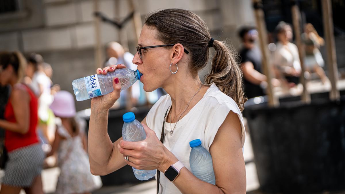 Segunda ola de calor, una mujer trata de hidratarse en el centro de Barcelona, en la plaza Catalunya