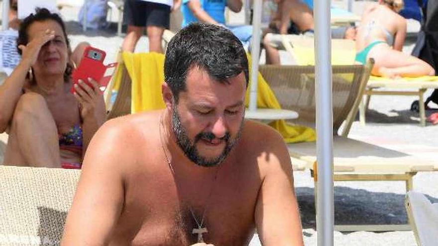 Salvini consulta su móvil en una playa de Taormina (Sicilia). // Efe