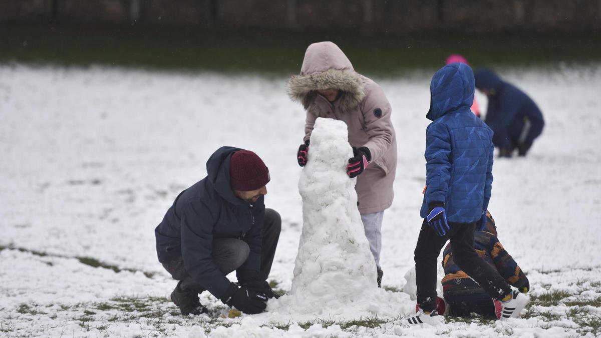 Tres niños montan un muñeco de nieve