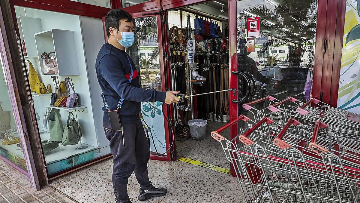 Desinfección de carros en una tienda en un polígono de Elche, donde ya cierran almacenes.