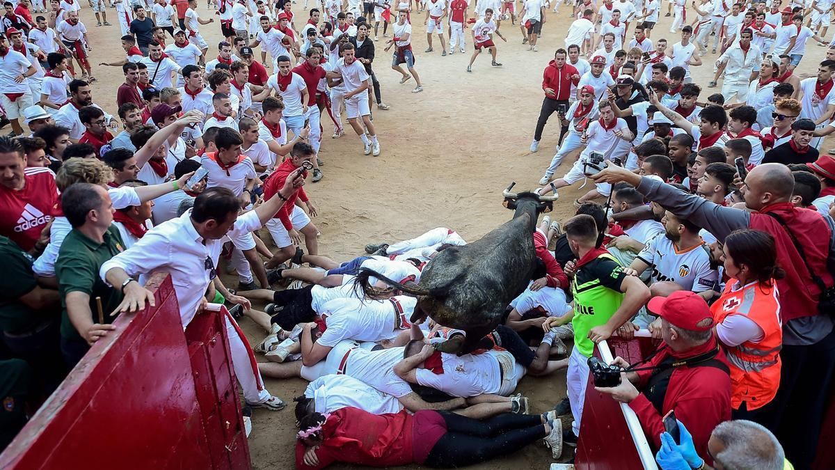 Una vaca joven salta sobre los participantes tras el encierro del cuarto día de San Fermín 2022.