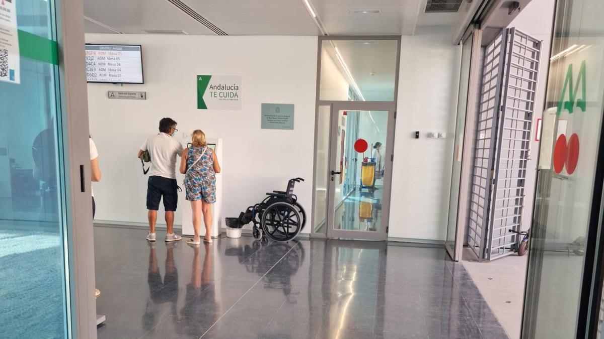 Dos usuarios, ante  una máquina de información en uno de los accesos al centro de salud.