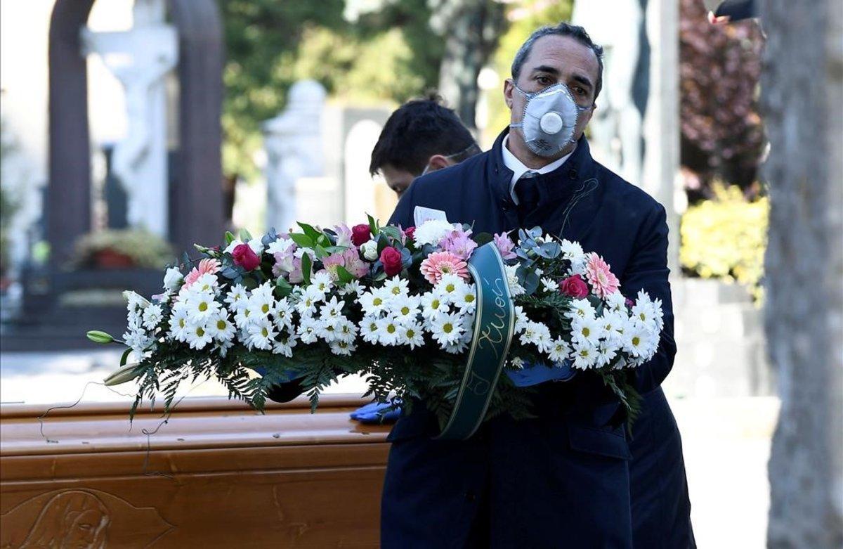 Trabajadores de un cementerio trasladan un féretro, en el cementerio de Bérgamo, Italia.