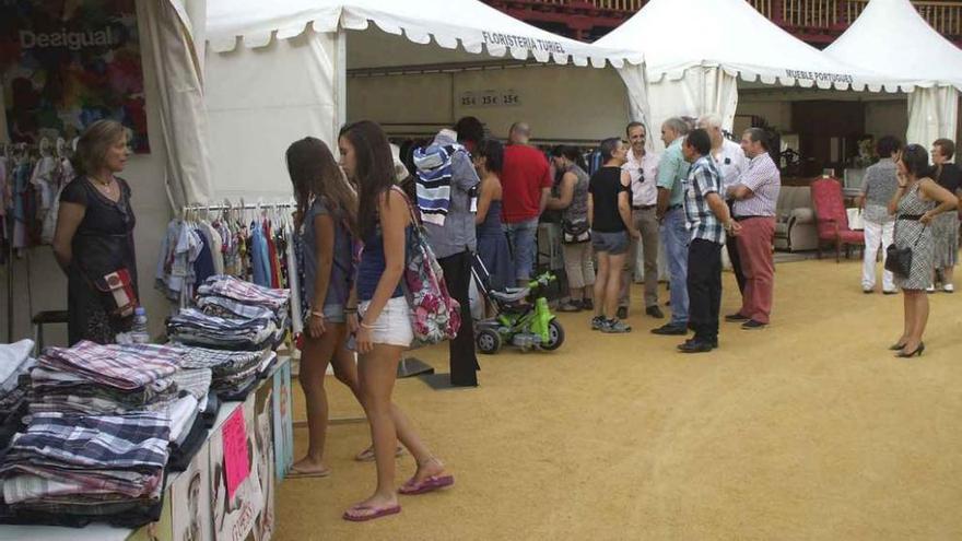 Visitantes recorren los puestos de venta instalados en la plaza de toros de la ciudad.