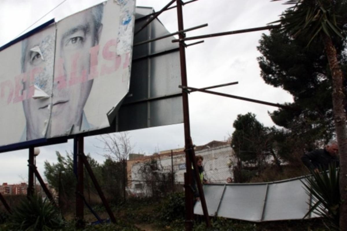 Operaris de la brigada municipal de Valls retiren un cartell amb desperfectes causats pel fort vent.