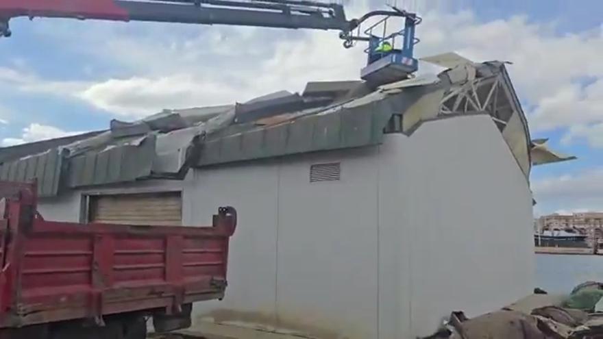 Una grúa eleva a un trabajador al techo de un almacén del Puerto de Mazarrón.