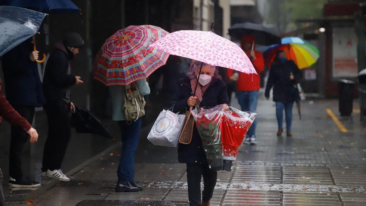 Cordobeses caminan bajo el paraguas este viernes, en un día protagonizado por las intensas lluvias.