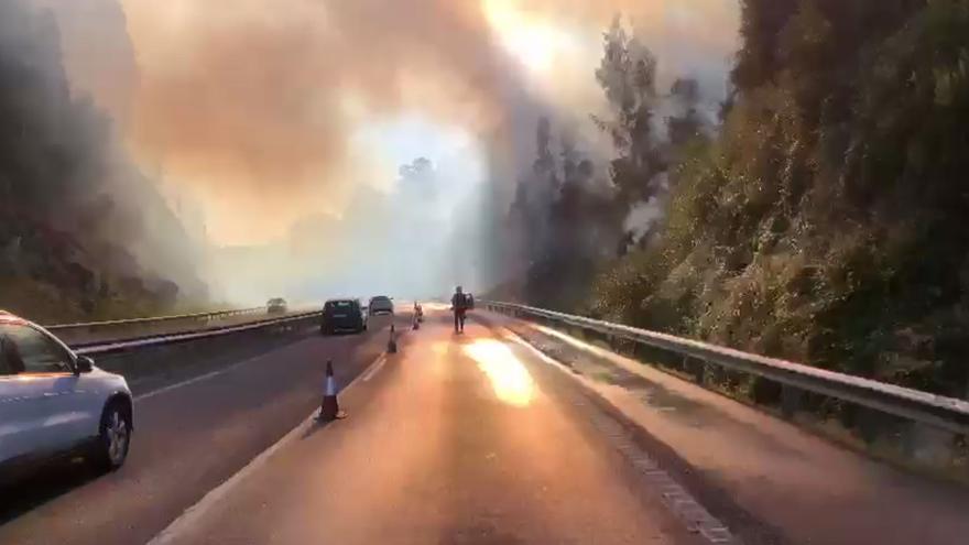 Un fuego en un coche pasa al monte, obliga a cortar la AP-9 y causa grandes retenciones