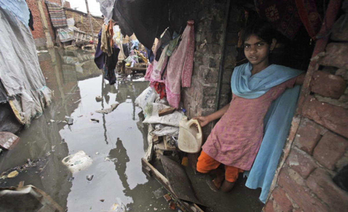 Una jove afectada per les inundacions es prepara per anar a buscar aigua potable a través del fang en una barriada a prop del riu Yamuna, a Nova Delhi, Índia.