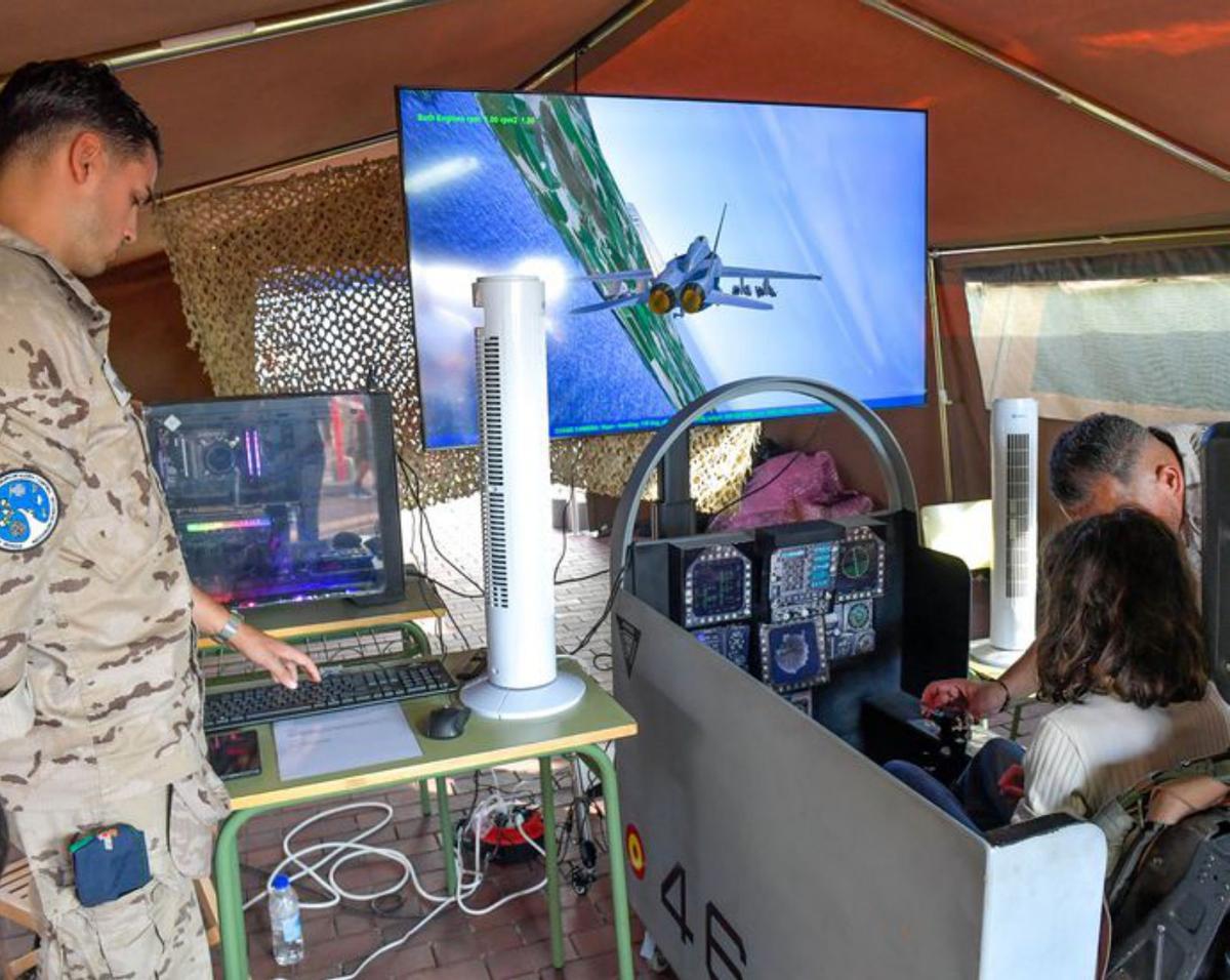 A la izquierda, una niña prueba un simulador virtual y, a la derecha, los asistentes contemplan un desfile aéreo. | | JUAN CASTRO