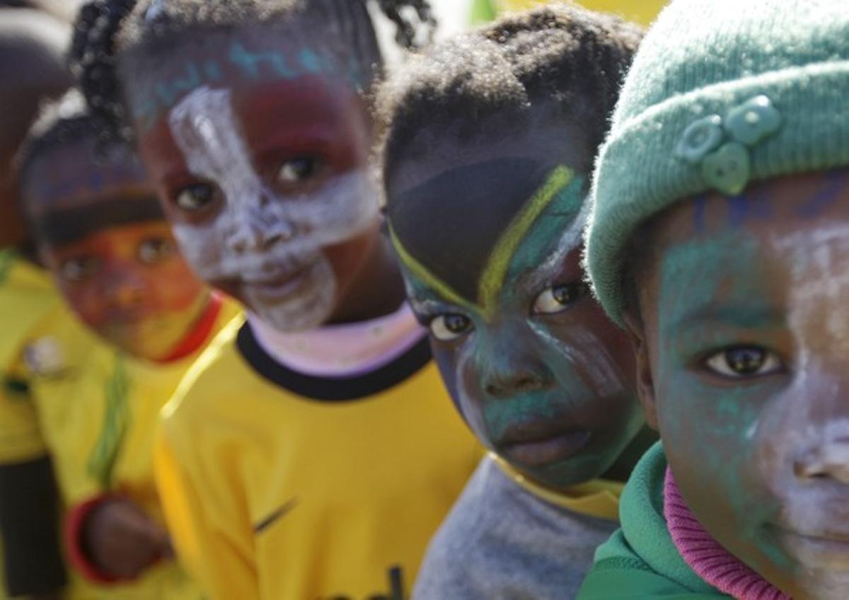 Uns nens amb la cara pintada esperen en fila per veure una rèplica del trofeu exposat a Soweto.