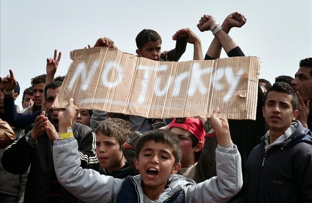 Refugiados e inmigrantes del puerto griego de Chios gritan eslóganes contra Turquía.