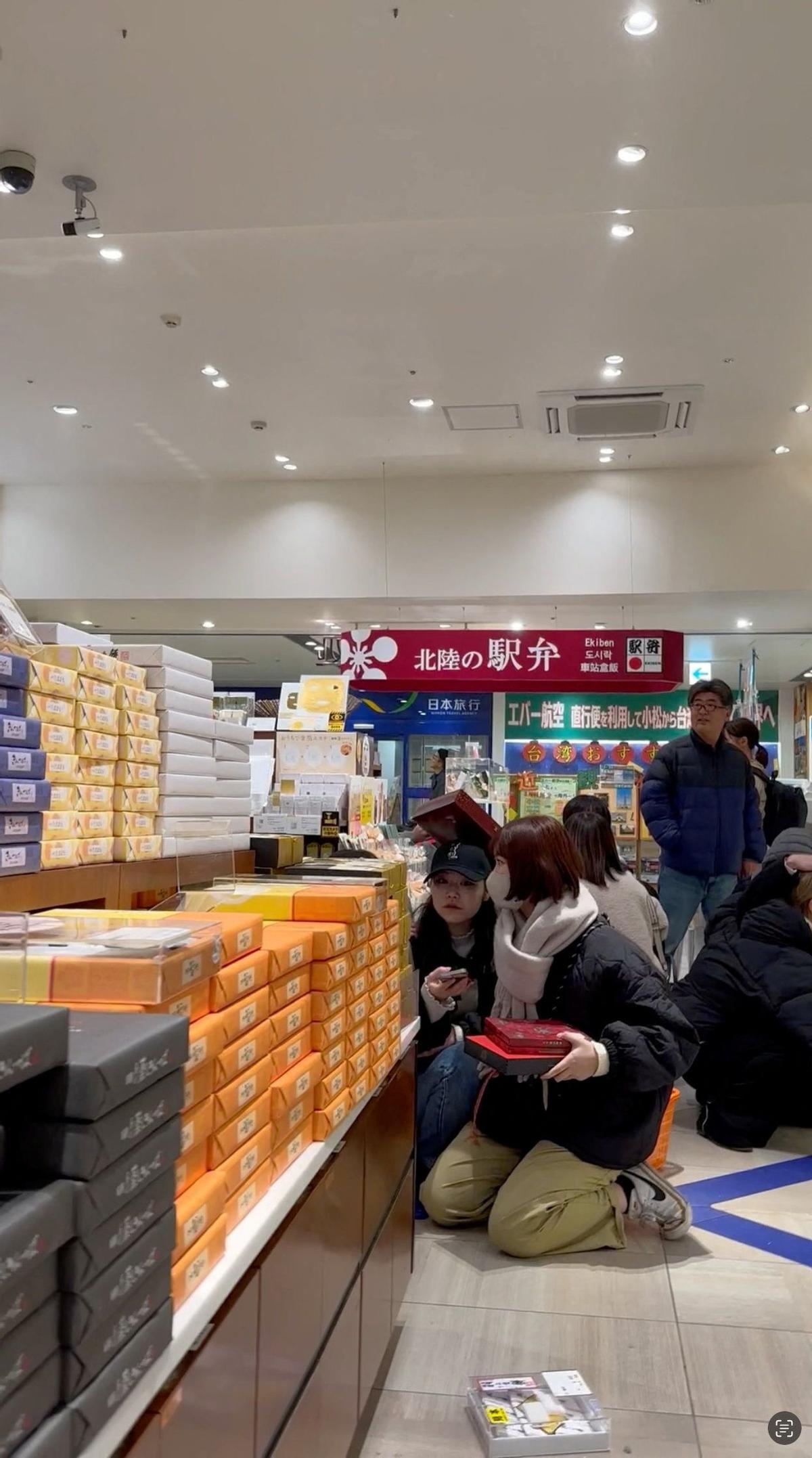 La gente se sienta en el suelo mientras los artículos caen de los estantes en una tienda mientras ocurre un terremoto, en Kanazawa, Ishikawa, Japón