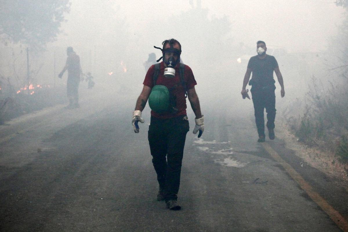 Ciudadanos voluntarios y bomberos caminan entre el abundante humo, mientras trabajan unidos para parar el fuego en Oren, en la región vacacional de Mugla, en Turquía.