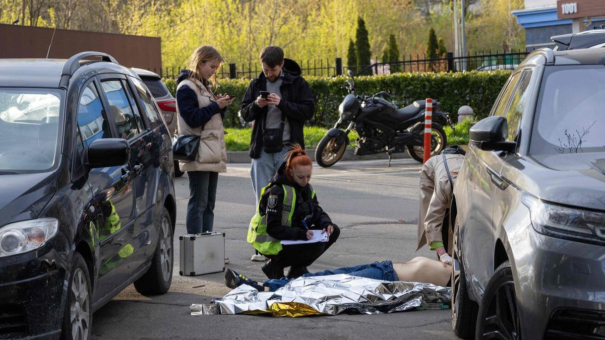 Policías examinan el cuerpo de una persona abatida por un hombre armado frente a un supermercado en Kiev este sábado