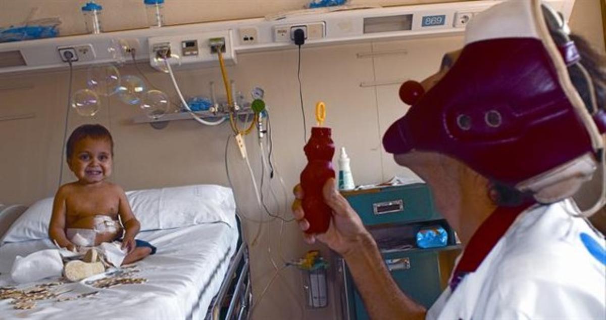 Soleimán Sumar, en diàlisi peritoneal, miraextasiat les bombolles que fabrica el Dr. Anestesio, del col·lectiu Pallapupas, a l’Hospital Sant Joan de Déu. Soleimán Sumar, en diàlisi peritoneal, miraextasiat les bombolles que fabrica el Dr. Anestesio, del col·lectiu Pallapupas, a l’Hospital Sant Joan de Déu.
