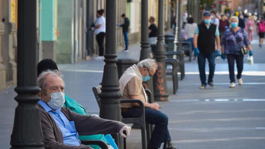 Ciudadanos que descansan o pasean por la calle Triana, en la capital.