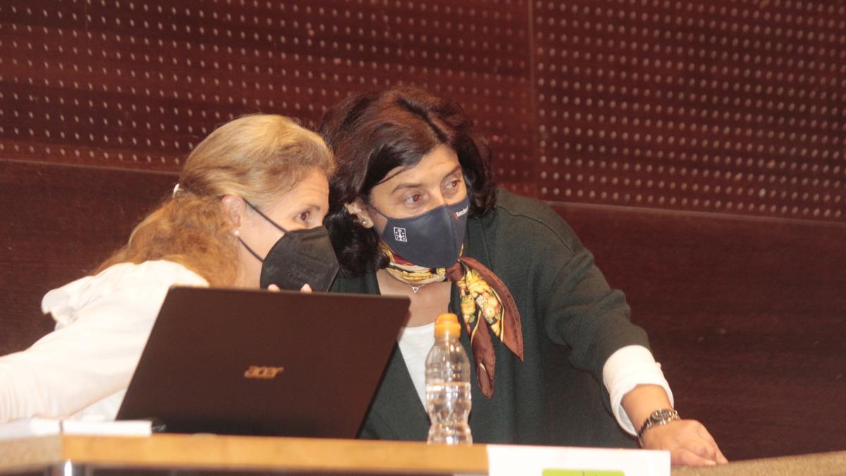 Elena Estévez conversa con la secretaria municipal durante un receso en un pleno municipal de Bueu.