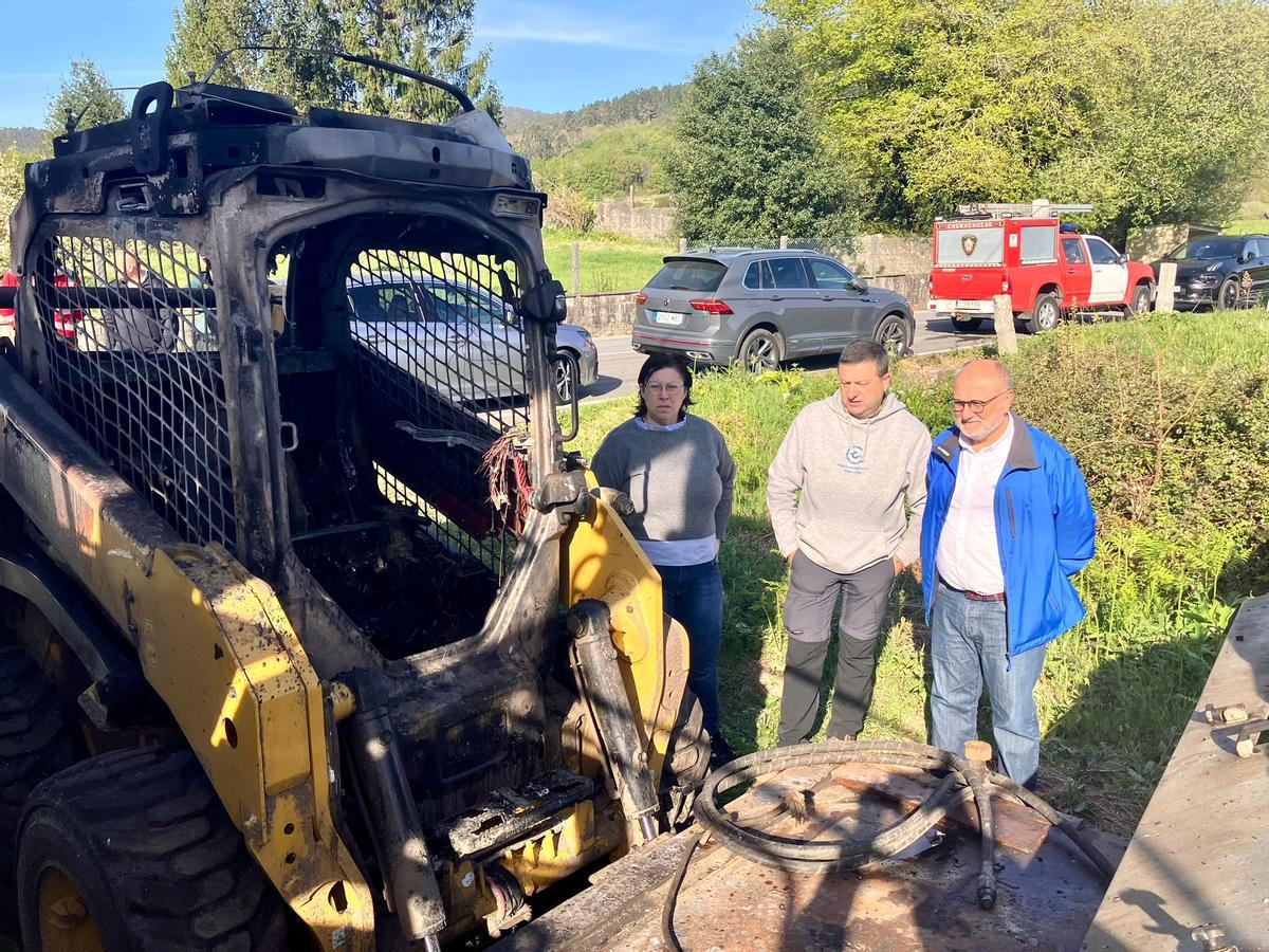 El subdelegado del Gobierno (d.) ante la excavadora incendiada.