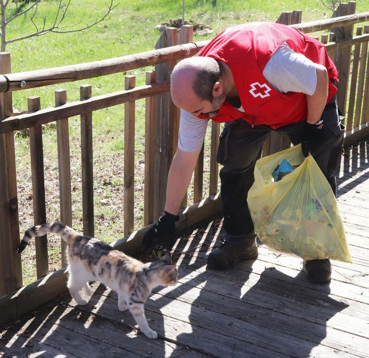 Un voluntario recogiendo basura por el entorno del parque infantil. | E. P.