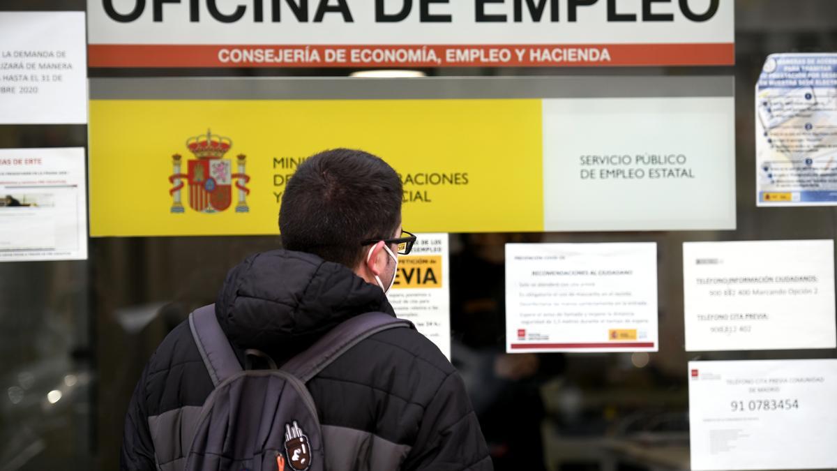 Un joven frente a una oficina de empleo.