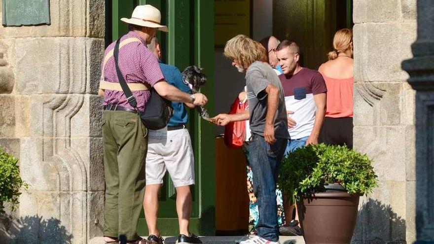 Un hombre recibe limosna a la entrada de la capilla de A Peregrina. // Rafa Vázquez