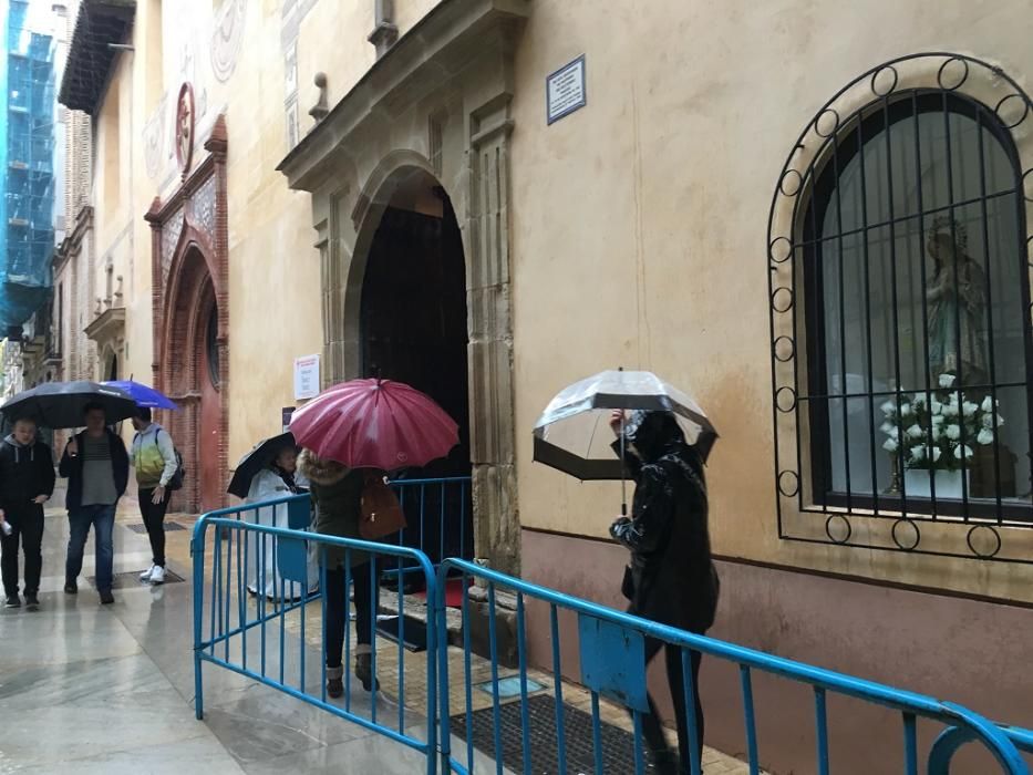 Cientos de malagueños acuden a rendirle devoción al Cristo de Medinaceli pese a la lluvia.