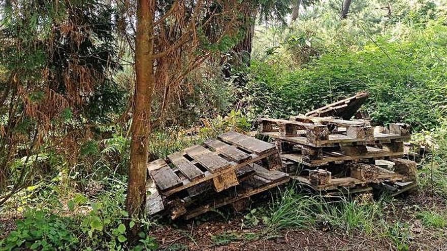 Un televisor y otros residuos en O Bañil y abajo palés en zona verde en Breixo.