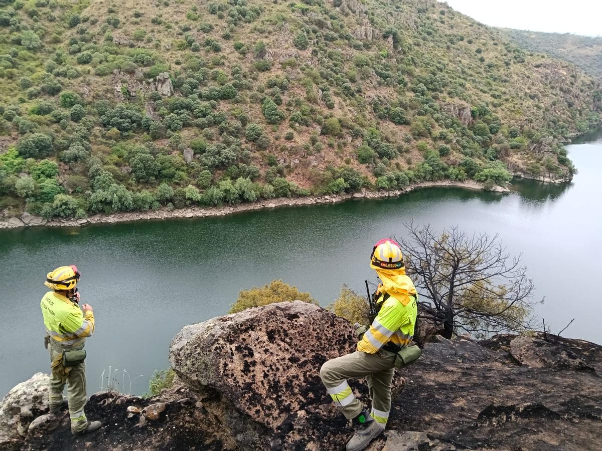 Dos bomberos forestales vigilan una zona de los Arribes para contener posibles reactivaciones.
