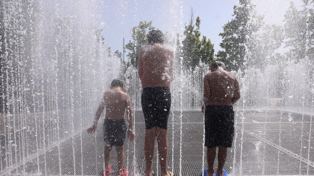 Tres niños se refrescan en una fuente de Zaragoza, en una imagen de archivo