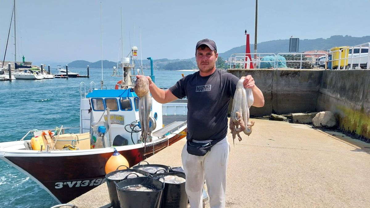 Un marinero de Bueu muestra hoy a mediodía dos pulpos tras el primer día de la campaña.