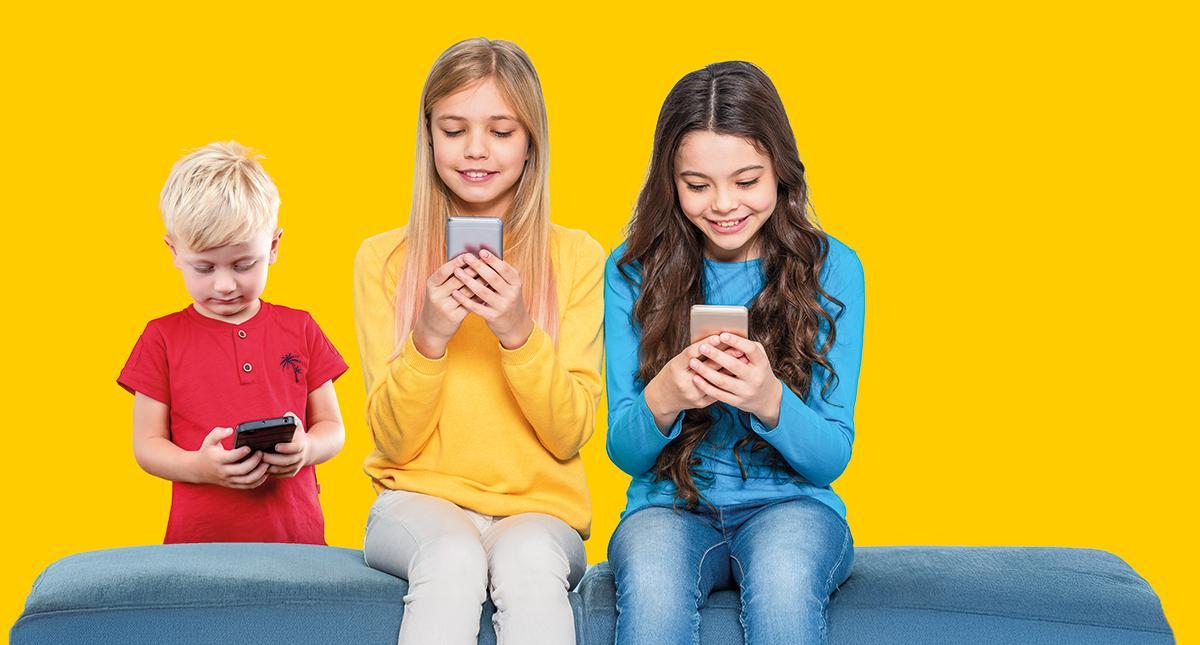 Dos niñas y un niño con un móvil en sus manos.
