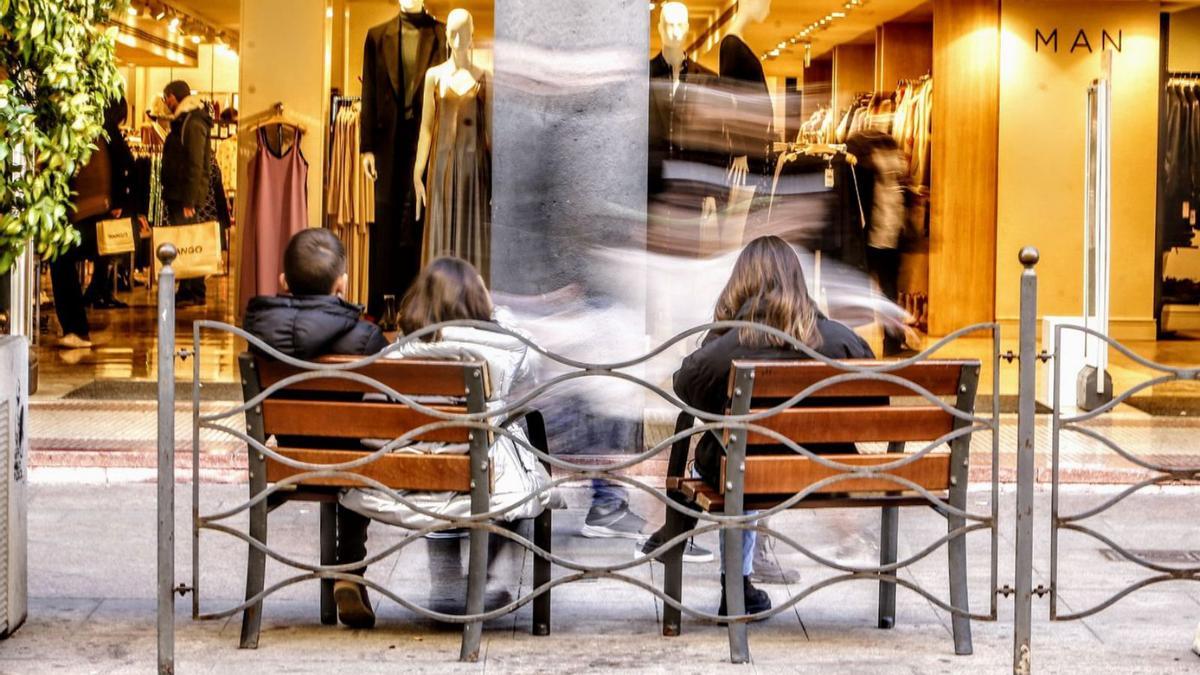 Varias personas descansan en los bancos frente a un escaparate en Maisonnave 