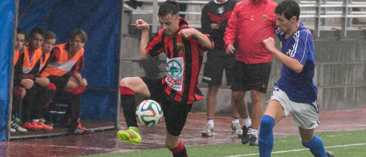 Un momento del partido a la altura del banquillo del Colegio Norte, encuentro que estuvo pasado por agua debido a la lluvia.