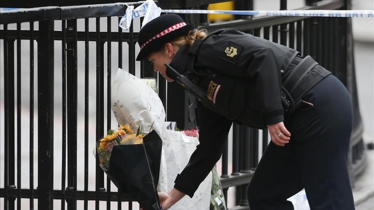 Un policía hace una ofrenda floral cerca de puente de Londres.