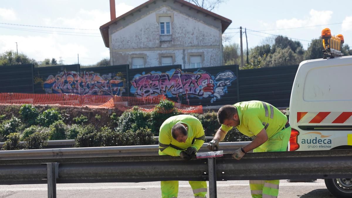 Dos de los trabajadores de las obras, con pantallas ya instaladas llenas de pintadas al fondo.