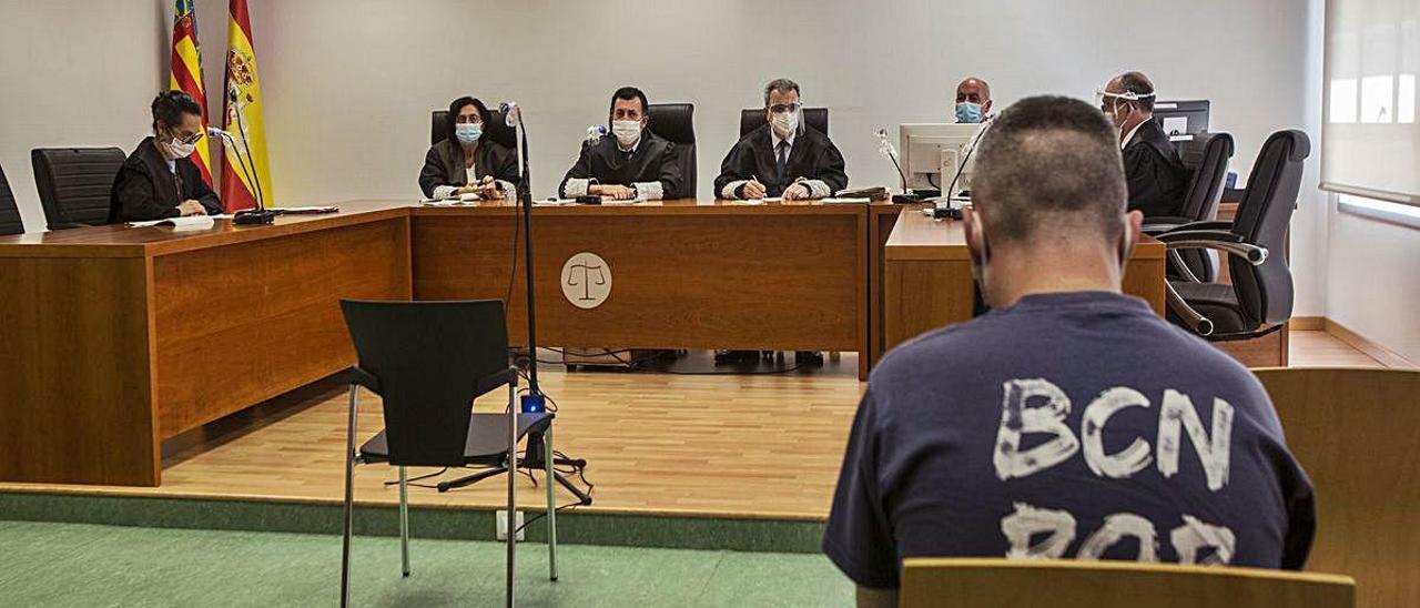 El acusado frente al tribunal, todos con mascarillas, durante el inicio del juicio.