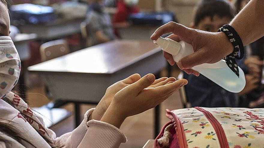 Una profesora desinfecta las manos de una niña. | Emilio Fraile