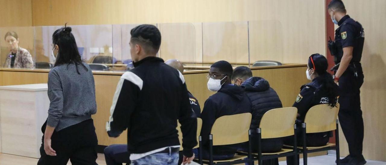En primer término, el joven que denunció su secuestro, con los dos acusados, en el banquillo, custodiados por la Policía Nacional, este miércoles, ante el tribunal de la sección octava de la Audiencia. | M. L.