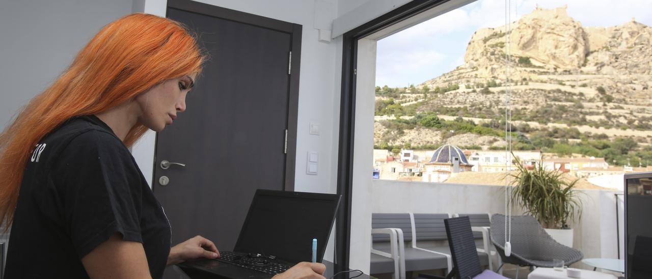 Una joven trabaja en un apartamento de alquiler con vistas al castillo de Santa Bárbara en Alicante